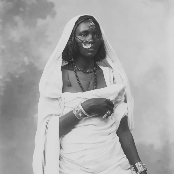Portrét africké ženy v tradičním oděvu, zdobené ozdobnými šperky.